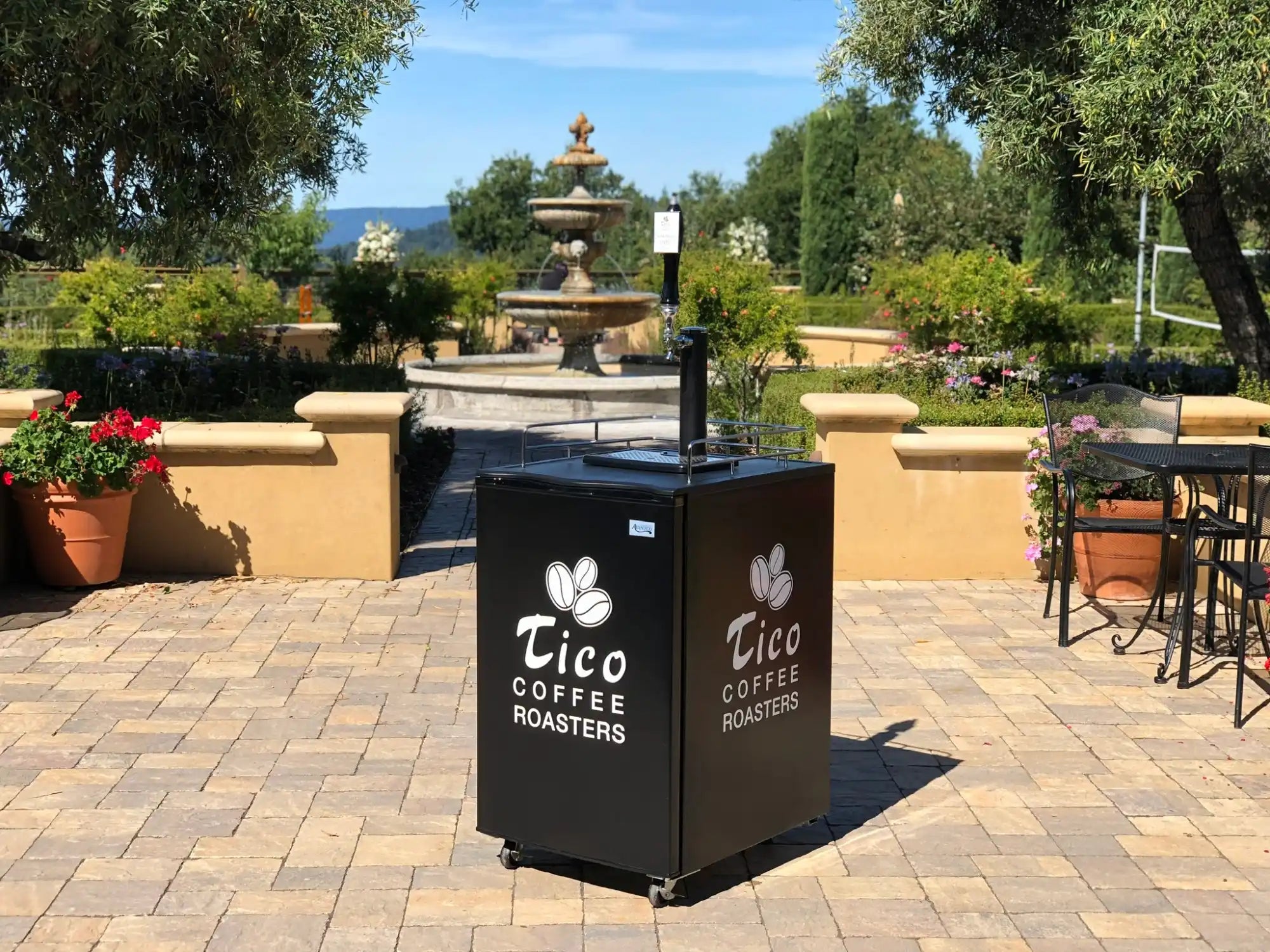 Black metal coffee station with the Cico Coffee Roasters logo featuring white tulip designs.