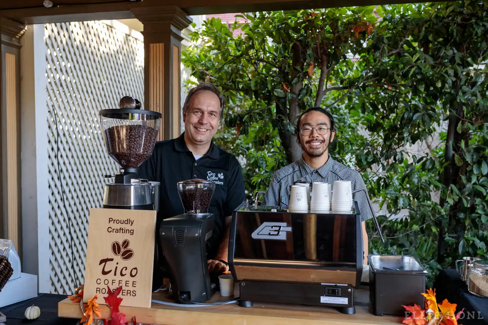 Coffee shop service counter with baristas and brewing equipment.