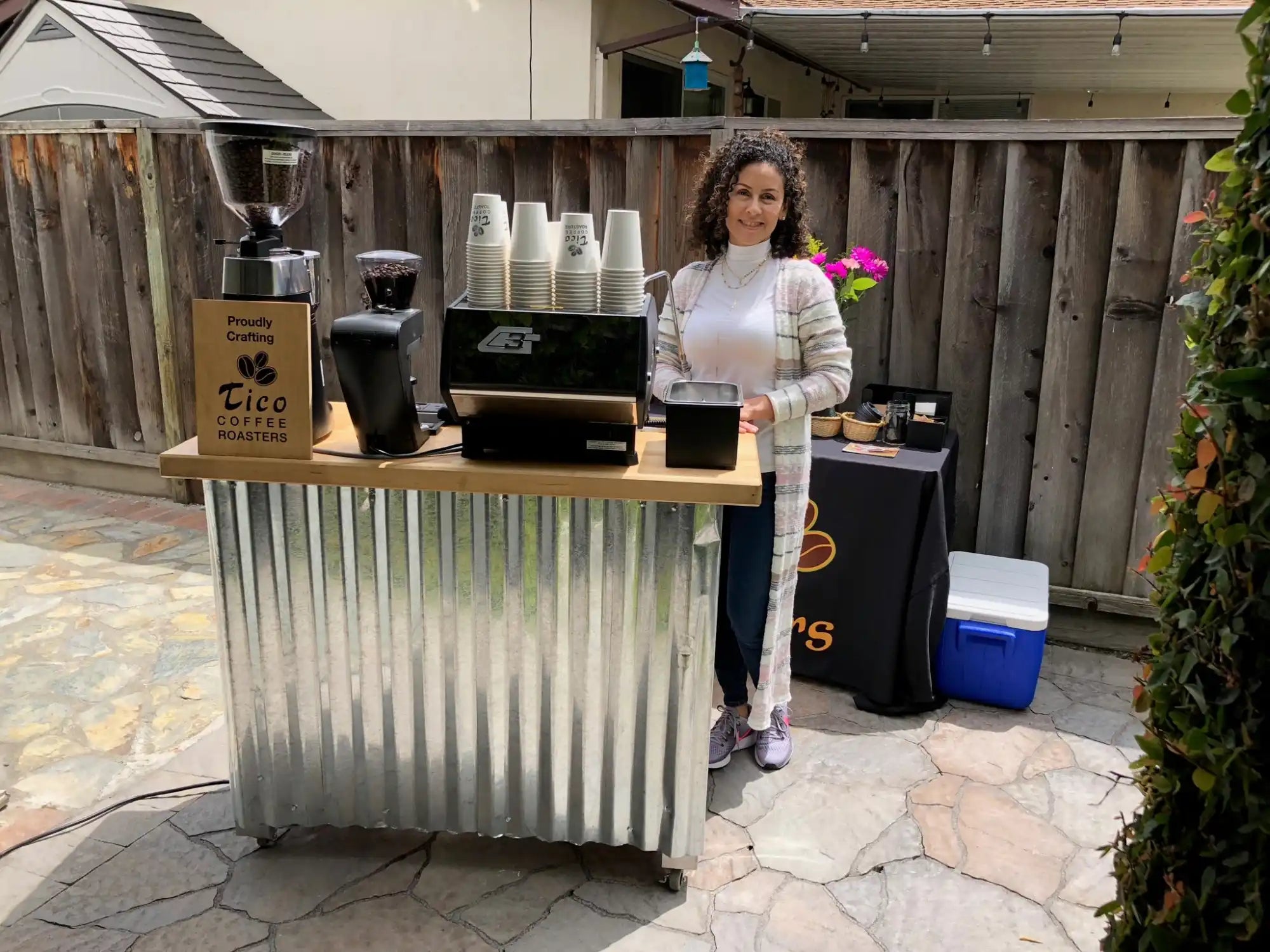 Mobile coffee cart with corrugated metal paneling and a wooden countertop.